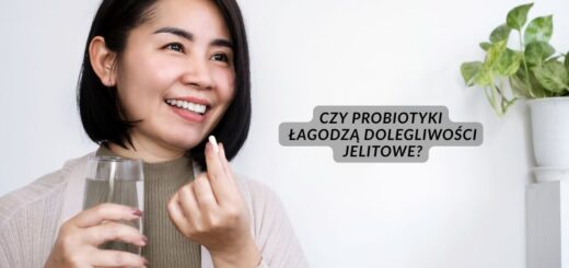 Uśmiechnięta kobieta przyjmuje kapsułkę probiotyku i trzyma szklankę wody – grafika do artykułu o wpływie probiotyków na dolegliwości jelitowe.