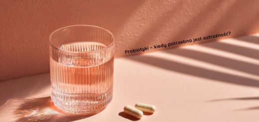 Szklanka wody i dwie kapsułki probiotyku leżące na jasnym tle, z napisem ‘Probiotyki – kiedy potrzebna jest ostrożność?’, symbolizujące temat bezpieczeństwa stosowania probiotyków.