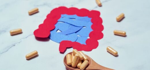 Ilustracja jelit otoczona kapsułkami probiotycznymi, symbolizująca temat mikrobioty oraz różnice między probiotykami, postbiotykami, synbiotykami, psychobiotykami i mykobiotykami.